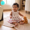 Small Baby girl wearing a muslin frock with Red Lady bug prints on it
